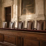 Banc des jurés vide dans une cour d'assises française, sous la plaque « La loi est l'expression de la volonté générale » — illustration de la disparition annoncée du jury populaire en appel prévue par le projet de loi SURE.