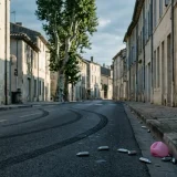 Rue urbaine au petit matin, traces de pneus et cartouches de protoxyde d'azote au sol, illustrant les phénomènes visés par la loi RIPOST